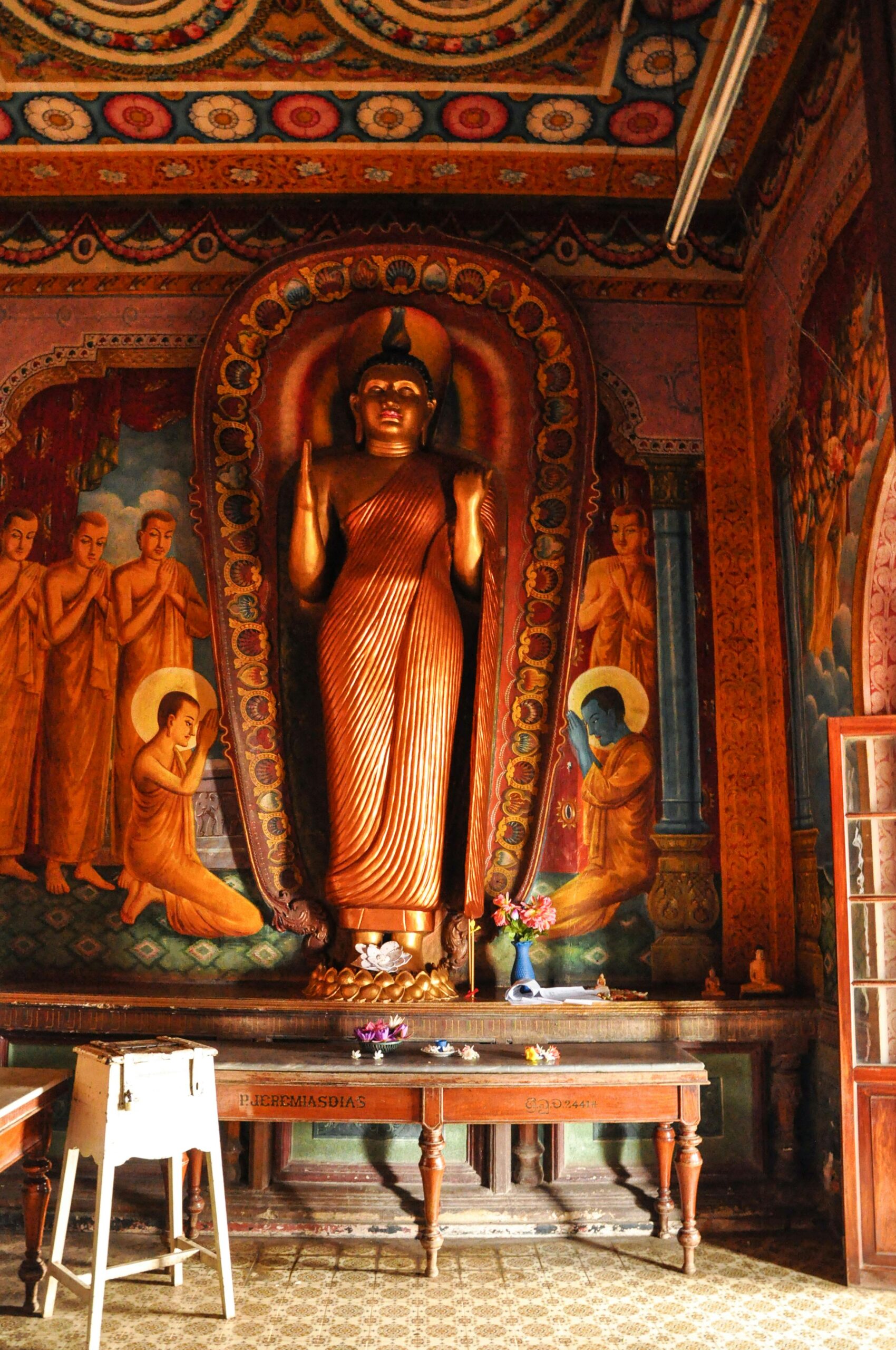 Intricate interior of a Buddhist temple in Panadura, featuring a Buddha statue and vibrant murals.