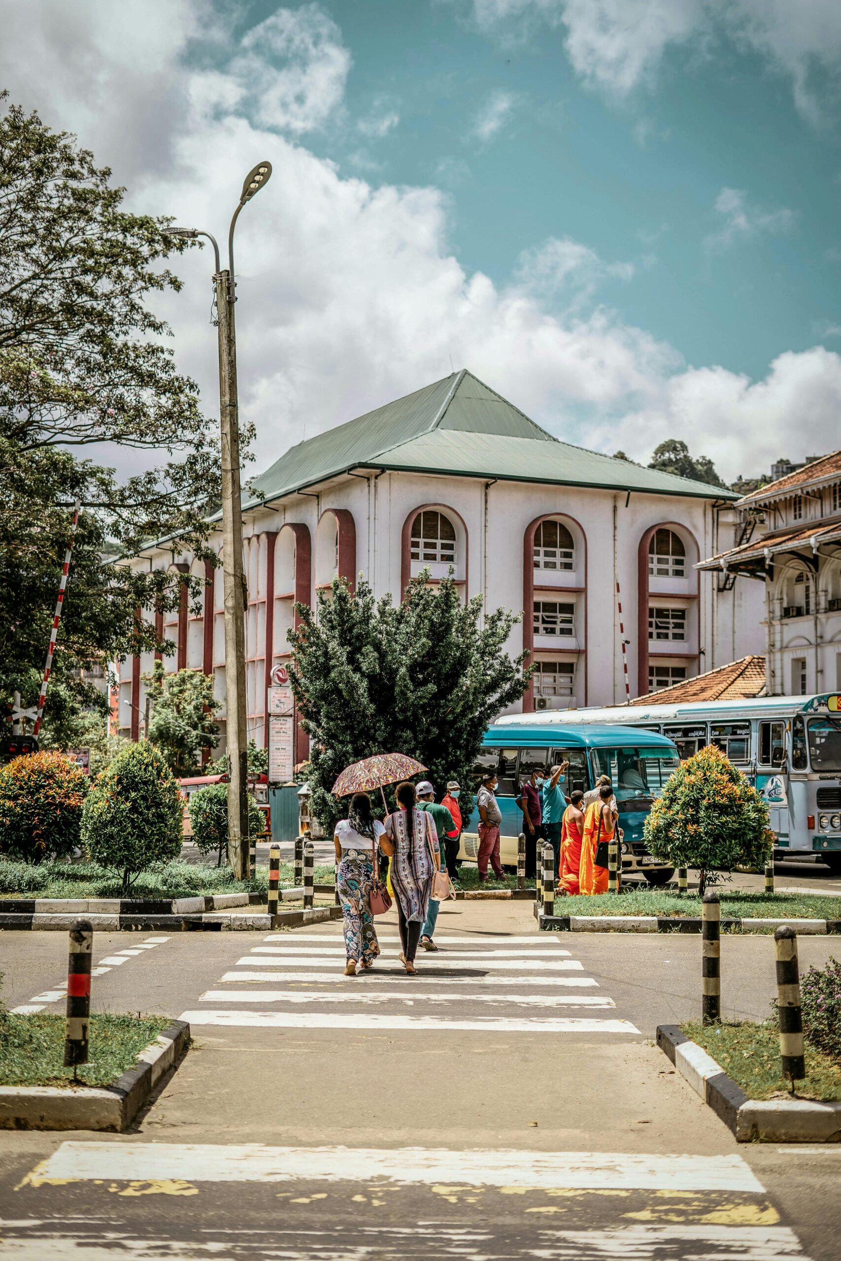 A bustling street scene in Hatton, Sri Lanka with pedestrians using a crosswalk and vibrant city life.